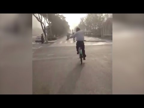 chinese man practices tai chi while riding bike